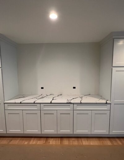 A kitchen with white cabinets and marble counter tops.