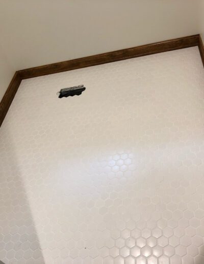 A bathroom with a white tile floor and wood trim.