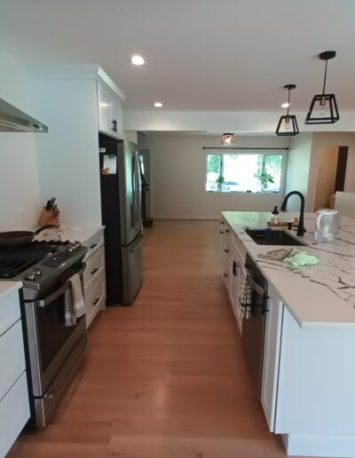 A kitchen with white cabinets and marble counter tops.