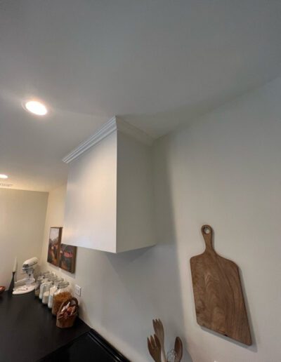 A kitchen with a white hood and a cutting board.