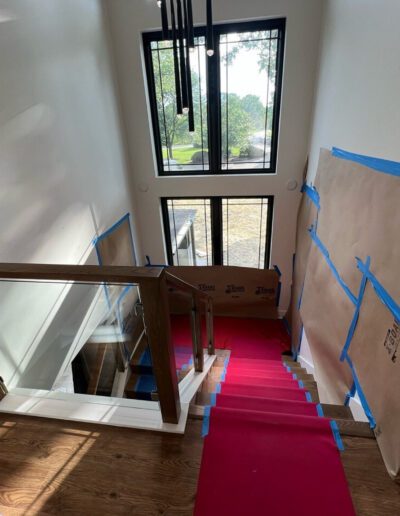 A stairway with a red carpet and a window.