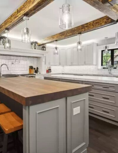 A white kitchen with wooden beams and stools.