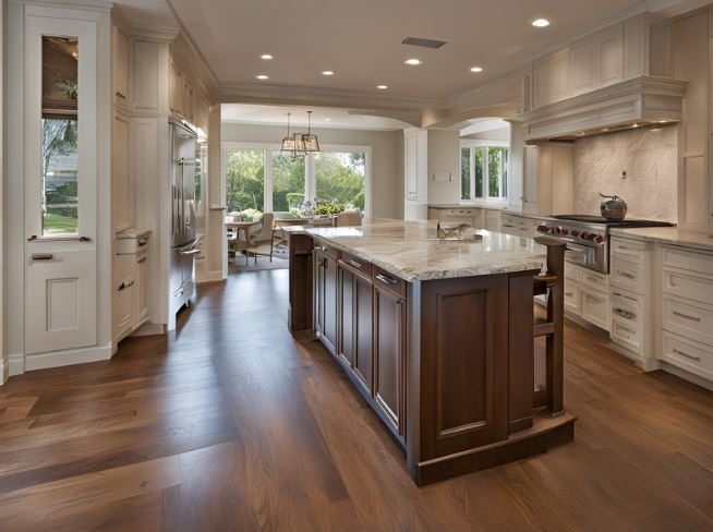 A spacious kitchen with wooden floors, white cabinets, a large marble-topped island, and stainless steel appliances, leading to a bright dining area with large windows.